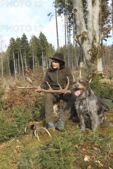 Huntress with a deer (Cervus elaphus) hunting dog Griffon at her side, Allgäu, Bavaria, Germany, Allgäu, Bavaria, Germany