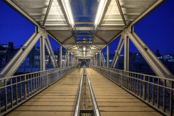 Illuminated pedestrian access jetty (bridge) to the Hamburg Landungsbrücken and jetty at night, Hamburg, Germany