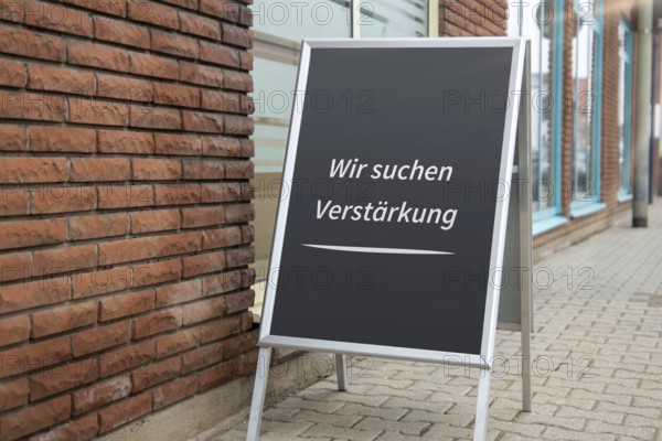 (photo montage) Display with the inscription WE ARE LOOKING FOR REINFORCEMENT in front of a shop