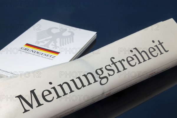 Symbolic newspaper with the headline FREEDOM OF SPEECH, with the German constitution in the background