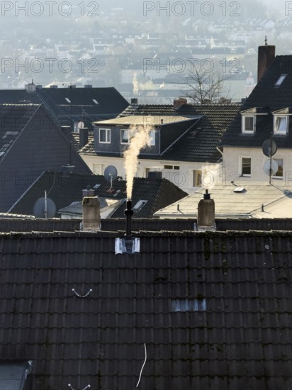 Smoke plume from a chimney over densely built residential area in the evening light, wintry city scene, Wuppertal, Germany