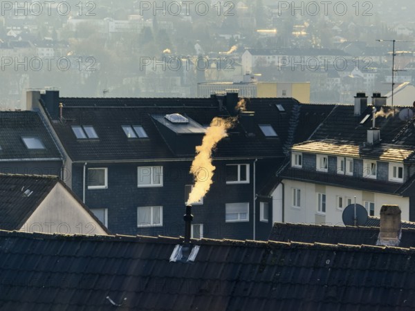 Smoke plume from a chimney over densely built residential area in the evening light, wintry city scene, Wuppertal, Germany