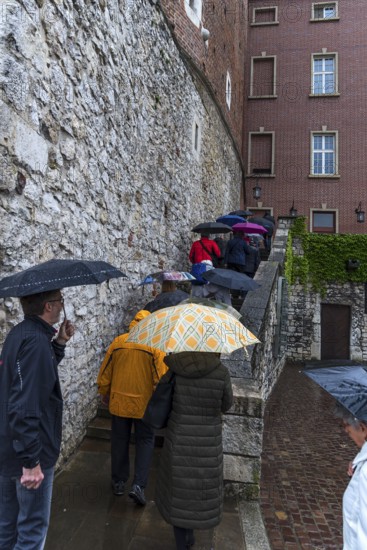 Tourists with umbrellas on Wavel Hill, Krakow, Poland