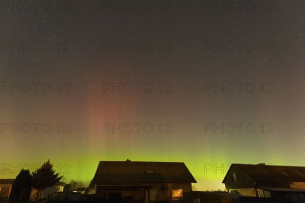 Shimmering red and green auroras over houses under clear starry skies, aurora borealis, Ilsede, Lower Saxony, Germany