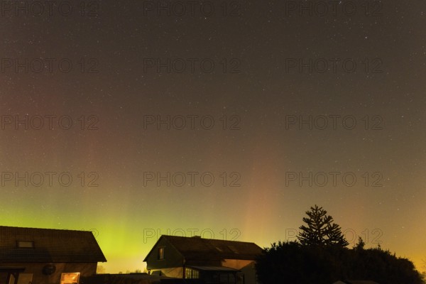 Green and pink polar lights over houses in the evening sky, starry sky, trees at night, aurora borealis, Ilsede, Lower Saxony, Germany