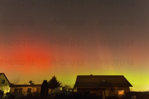 Red and green polar lights shine over houses, illuminated night sky, aurora borealis, Ilsede, Lower Saxony, Germany