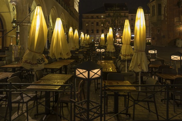 Illuminated umbrellas in a restaurant on the market square at night, Krakow, Poland