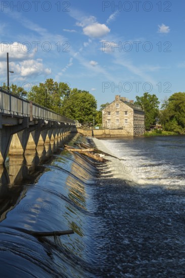 Moulin Neuf water flow control dam and walkway over Des Mille-Iles river plus New Mill on Ile des Moulins in summer, Old Terrebonne, Quebec, Canada