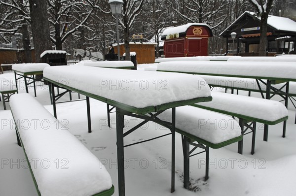 Winter in the English Garden, snow-covered beer garden tables and benches, Munich, Bavaria, Germany