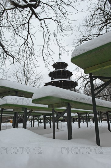 Winter in the English Garden, snow-covered beer garden tables and benches, Chinese Tower, Munich, Bavaria, Germany