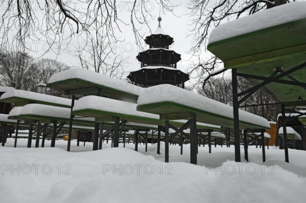 Winter in the English Garden, snow-covered beer garden tables and benches, Chinese Tower, Munich, Bavaria, Germany