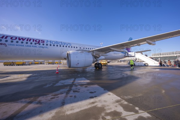 A Eurowings plane at an airport with people boarding a flight of stairs, Stuttgart Airport, Germany