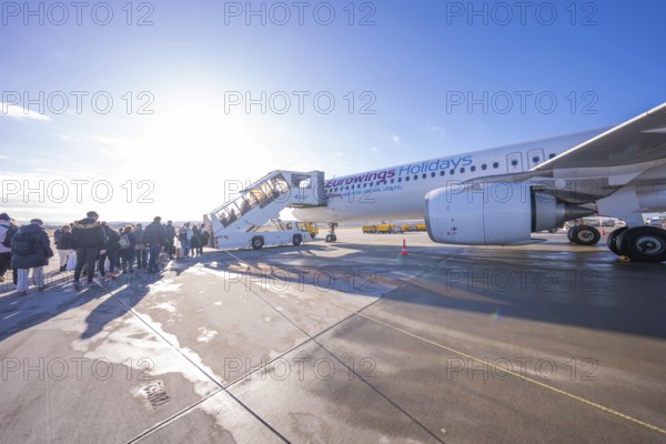 Passengers board an airplane via a mobile staircase under bright blue skies, Stuttgart Airport, Germany