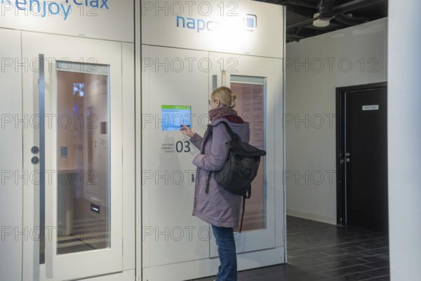 Woman operating screen on modern indoor sleeping cabin, Stuttgart Airport, Germany
