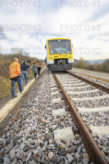 People in orange colors along the train on rails in a rural setting, acceptance of the Hermann Hessebahn, Calw, Germany