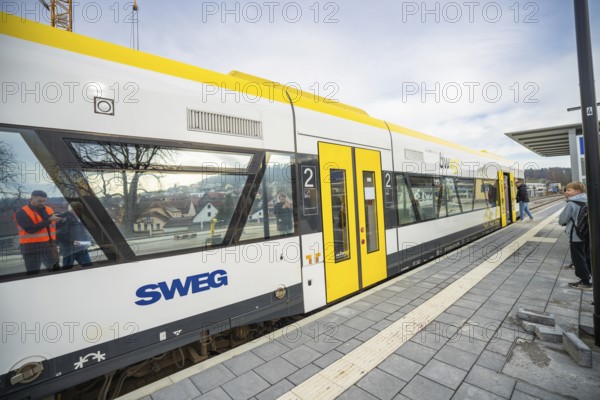 A yellow and white train is parked at a platform, passengers are waiting next to it, the Hermann Hessebahn, Calw, Germany