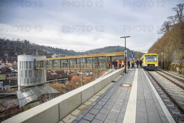 A train approaches a station with a wide panorama and hills in the background, taking off the Hermann Hessebahn, Calw, Germany