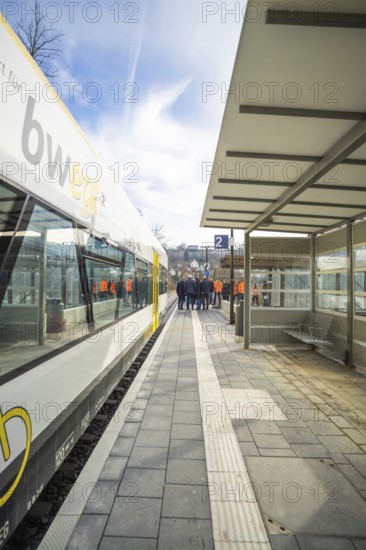 A train station with a stopping train and a group of people moving on the platform, acceptance of the Hermann Hessebahn, Calw, Germany