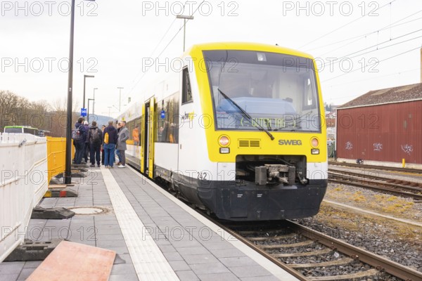Yellow SWEG vehicle parked on the platform with several people waiting, the Hermann Hessebahn ride, Calw, Germany