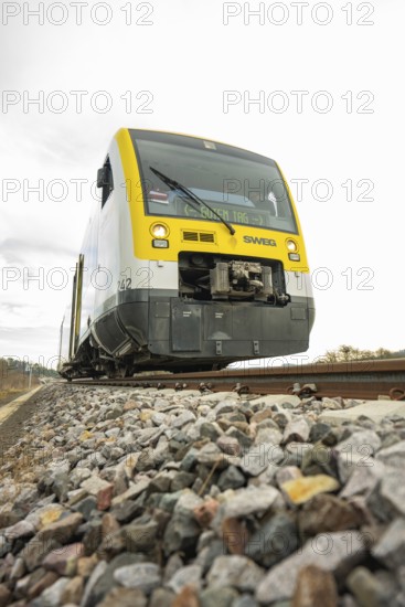 SWEG train on rails with pebbles in the foreground under cloudy sky, taking off the Hermann Hessebahn, Calw, Germany