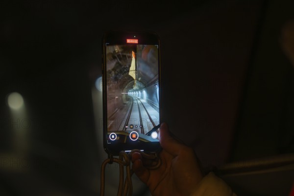 Smartphone shows video recording of an illuminated tunnel in a dark environment, the Hermann Hessebahn's journey, Calw, Germany