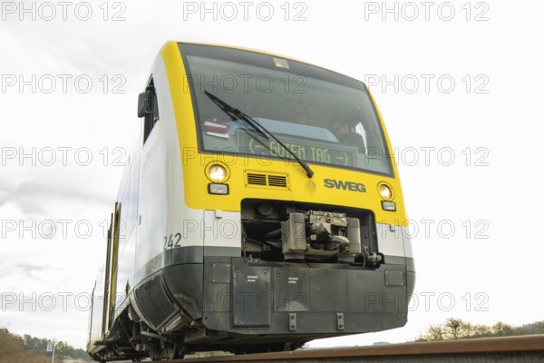 Yellow and grey SWEG vehicle on the rails against cloudy sky, taking off the Hermann Hessebahn, Calw, Germany
