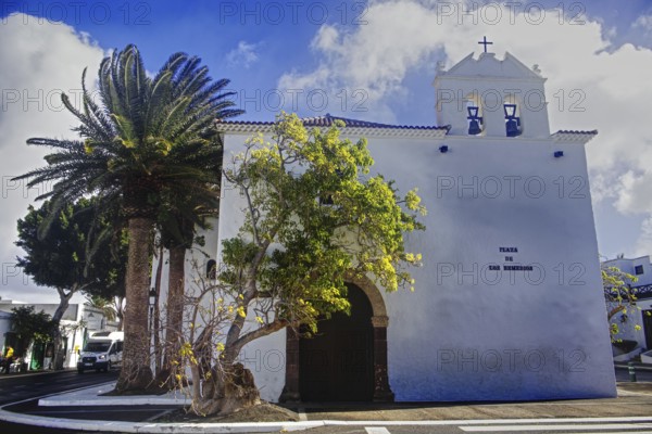 White church building with palm trees and blue sky in the background, Yaiza Lanzarote