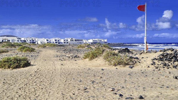 Red flag coast and adjacent village under clear skies, Caleta de Famara Lanzarote