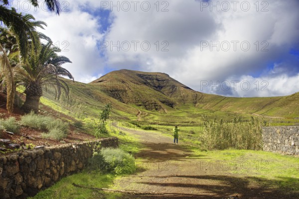 Green hills and walkers under cloudy sky, Yaiza Lanzarote