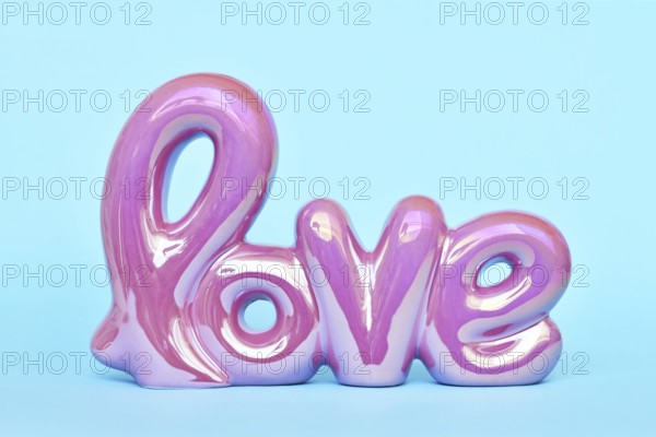 Shiny pink Valentine's day text ornament 'love' on pastel blue background