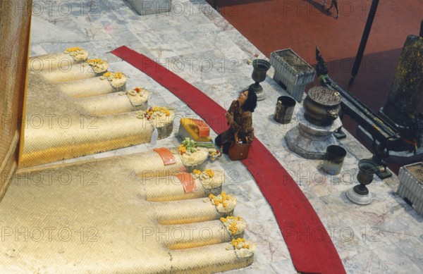 The huge golden Buddha at Wat Indravihan. A Buddhist woman prays at the feet of the big standing Buddha. Buddhism, religion, Bangkok, Thailand, Southeast Asia
