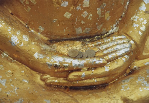Donations for the temple in the hands of a Buddha sculpture. Buddha, Buddhism, religion, Bangkok, Thailand, Southeast Asia