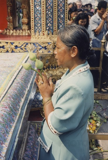 Wat Phra Kaeo, (Temple of the Emerald Buddha, official name Wat Phra Sri Rattana Satsadaram) praying Buddhist with lotus flowers. In Asia, the lotus flower symbolises purity, faithfulness, creativity and enlightenment. Buddha, Buddhism, Religion, Bangkok, Thailand, Southeast Asia