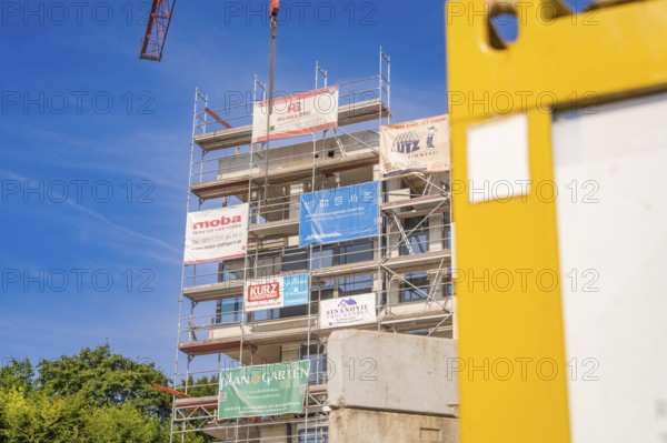 Multi-storey scaffolding structure with company logos on a sunny construction site, carpentry, new building, Stuttgart, Germany