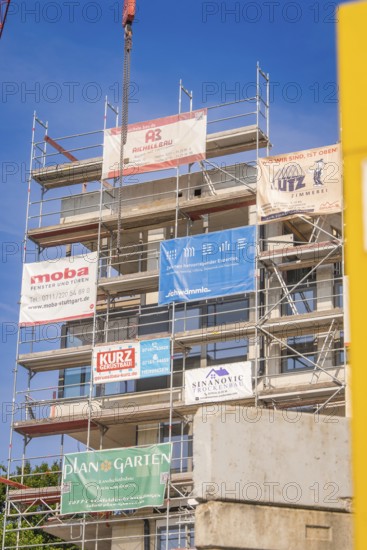 Multi-storey scaffolding on a building with various company banners, carpentry, new building, Stuttgart, Germany
