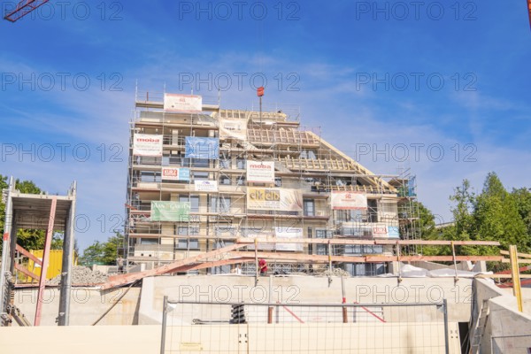 Building under construction with scaffolding and advertising banners under blue sky, carpentry, new building, Stuttgart, Germany