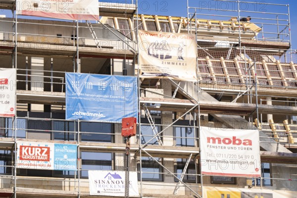 A scaffolding with various corporate advertising banners on a building, carpentry, new building, Stuttgart, Germany