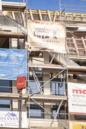 Partially finished building with scaffolding and transparent advertising for craftsmen, carpentry, new building, Stuttgart, Germany