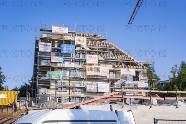 Multi-storey building with scaffolding and banners under clear, sunny sky, carpentry, new building, Stuttgart, Germany