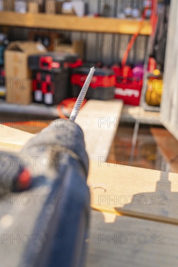 Blurred view of a drill on a construction site with wooden shelves in the background, carpentry, new building, Stuttgart, Germany