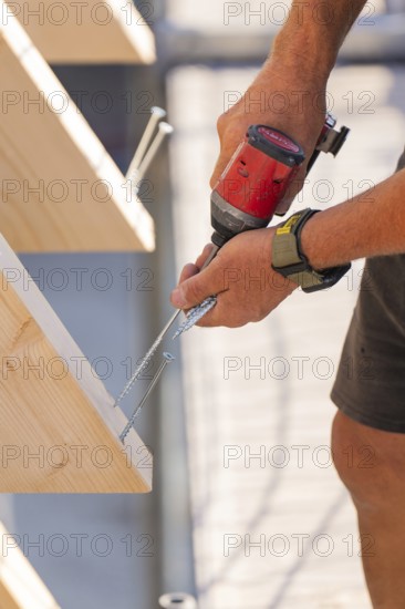 A craftsman drills a screw into a wooden board with precision, carpentry, new building, Stuttgart, Germany