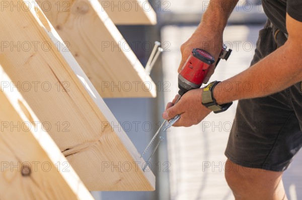 Close-up of a worker screwing a board with a drill, carpentry, new building, Stuttgart, Germany