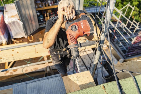 A construction worker uses a drill to work on wood in a construction project, carpentry, new building, Stuttgart, Germany