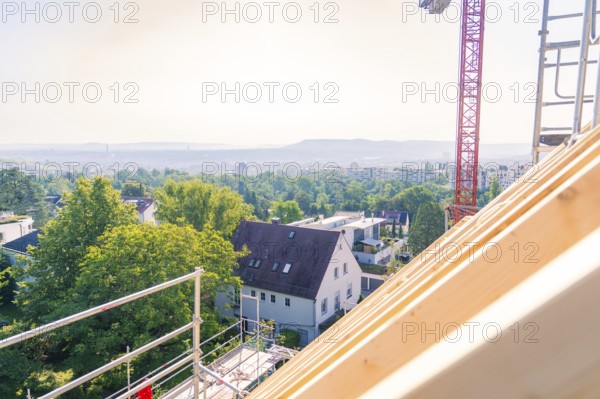 A view from a roof shows a landscape with trees and a crane in the background, carpentry, new building, Stuttgart, Germany