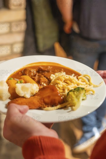 Plate with goulash and other garnishes carried by one person at a meal
