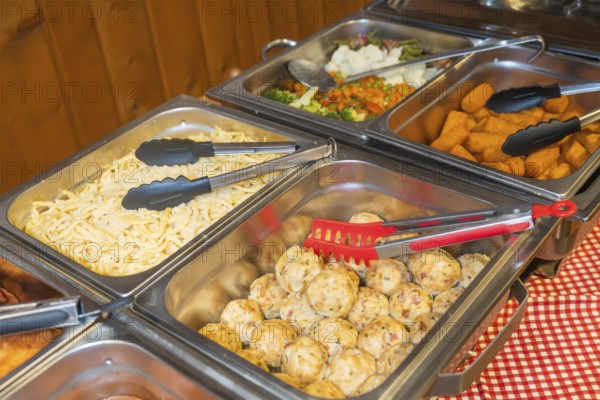 Buffet with various dishes such as cheese spaetzle, dumplings and salad