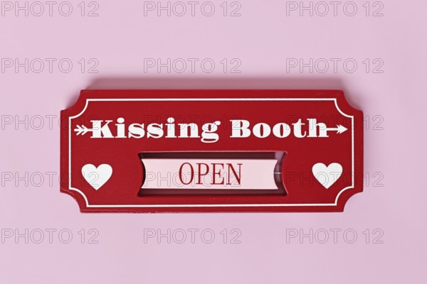 Valentine's Day kissing booth sign with hearts on pink background. Romantic love concept flat lay