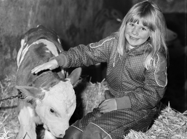 Little girl stroking a calf in a cowshed, on a former Franconian farm, black and white, Bavaria, Germany