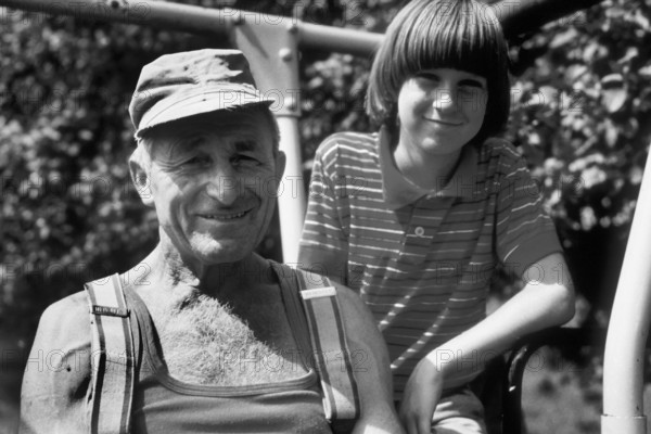 Farmer and his young assistant on the tractor, on a former Franconian farm, black and white, Bavaria, Germany