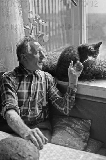 Farmer with a cat at the kitchen window, on a former Franconian farm, black and white, Bavaria, Germany